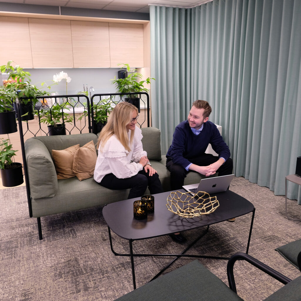 Dame og mann sitter i sofa. De ser på hverandre og smiler